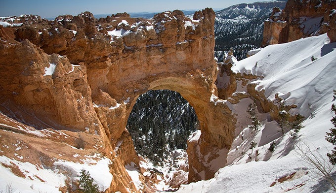 Bryce-Natural-Bridge-winter_DP_680 The Natural Bridge towers over snowy cliffs in Bryce Canyon