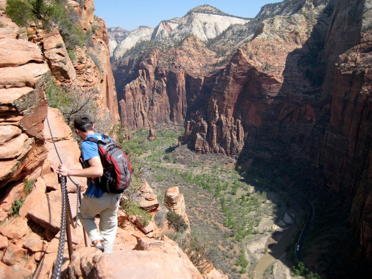 A hiker holding onto the chains on his way to Angel's Landing in Zion National Park, an ultimate Zion adventure